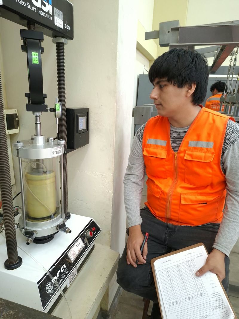 Tesista registrando datos durante un ensayo triaxial en el laboratorio